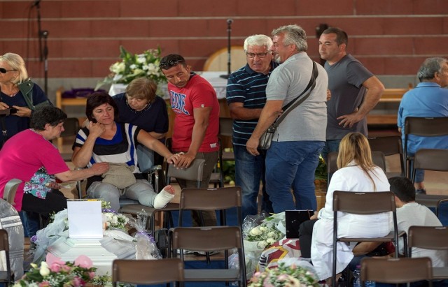 Mourners pay their respects as they attend a funeral for the earthquake victims inside a gym in Ascoli Piceno